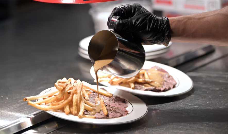 Steak and fries are finished with a topping of secret sauce at Medium Rare in Arsenal Yards.