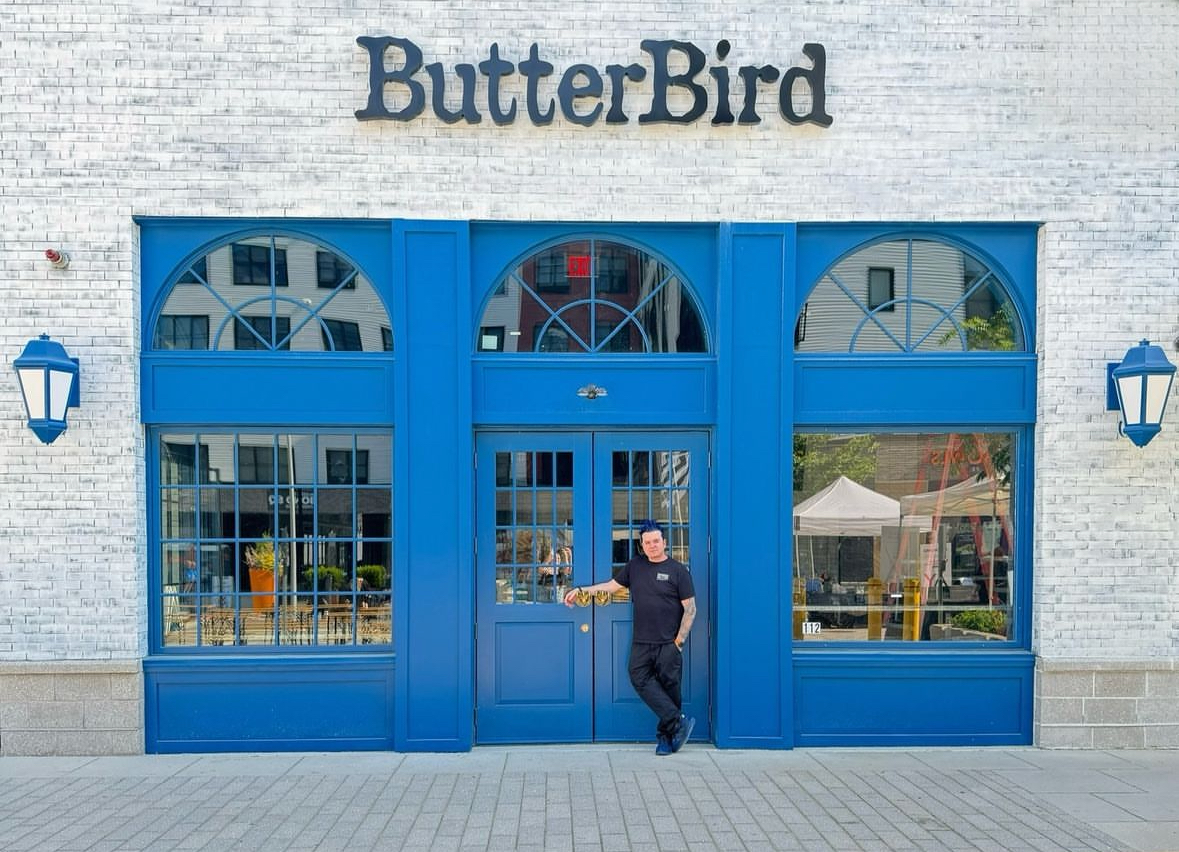 An image of Chef Jason Santos standing in front of the door of Butterbird at Arsenal Yards